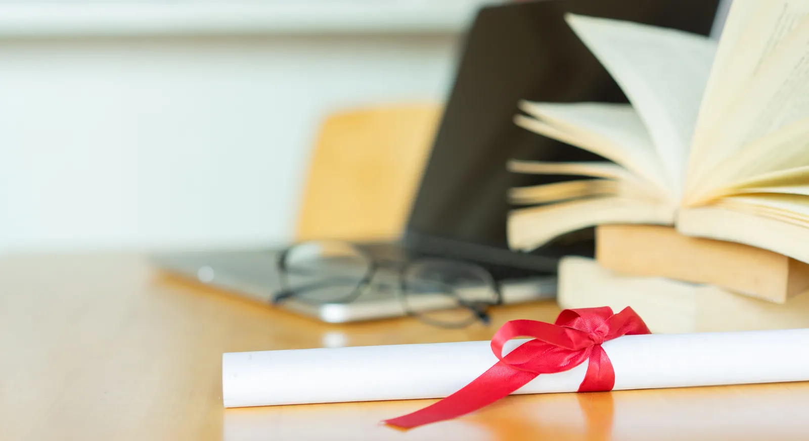 Books, a graduation diploma and notes laid on a desk